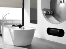 Bañera ovalada exenta de acero esmaltado en baño moderno con banco y grandes ventanas.